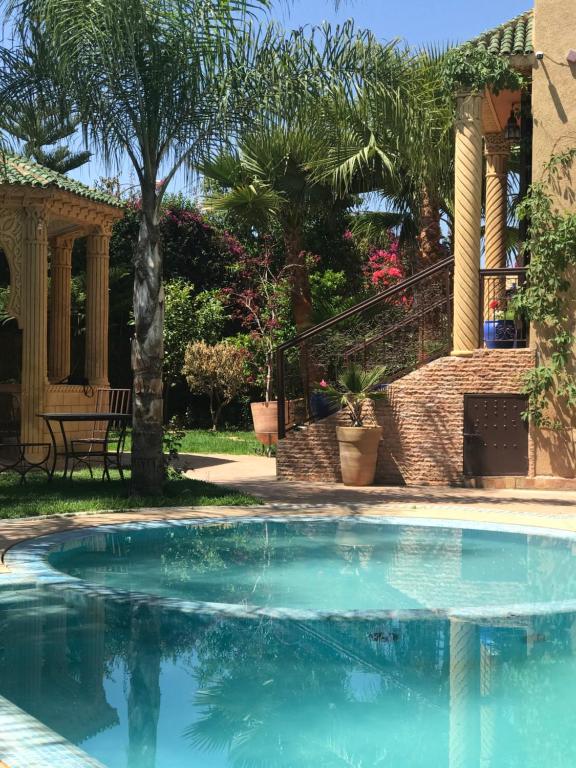 梅克内斯Les Jardins de Ryad Bahia的棕榈树屋前的游泳池