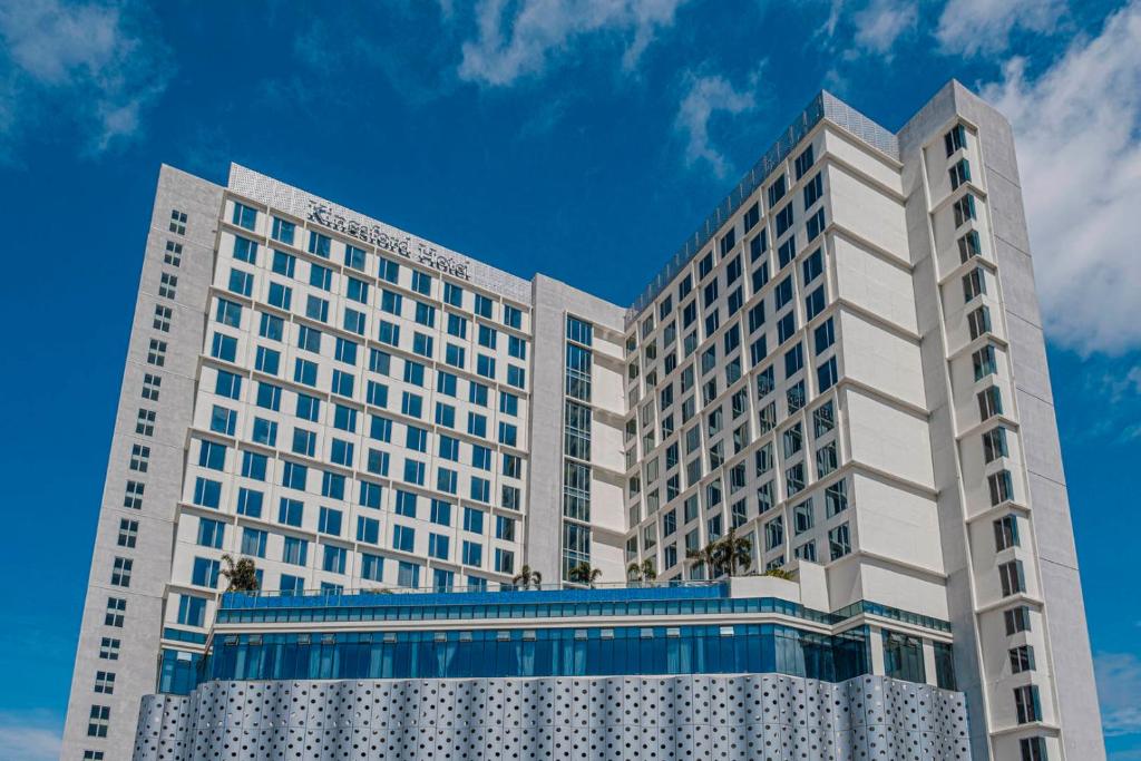 马尼拉Kingsford Hotel Manila的两座高大的白色建筑,面对蓝色的天空