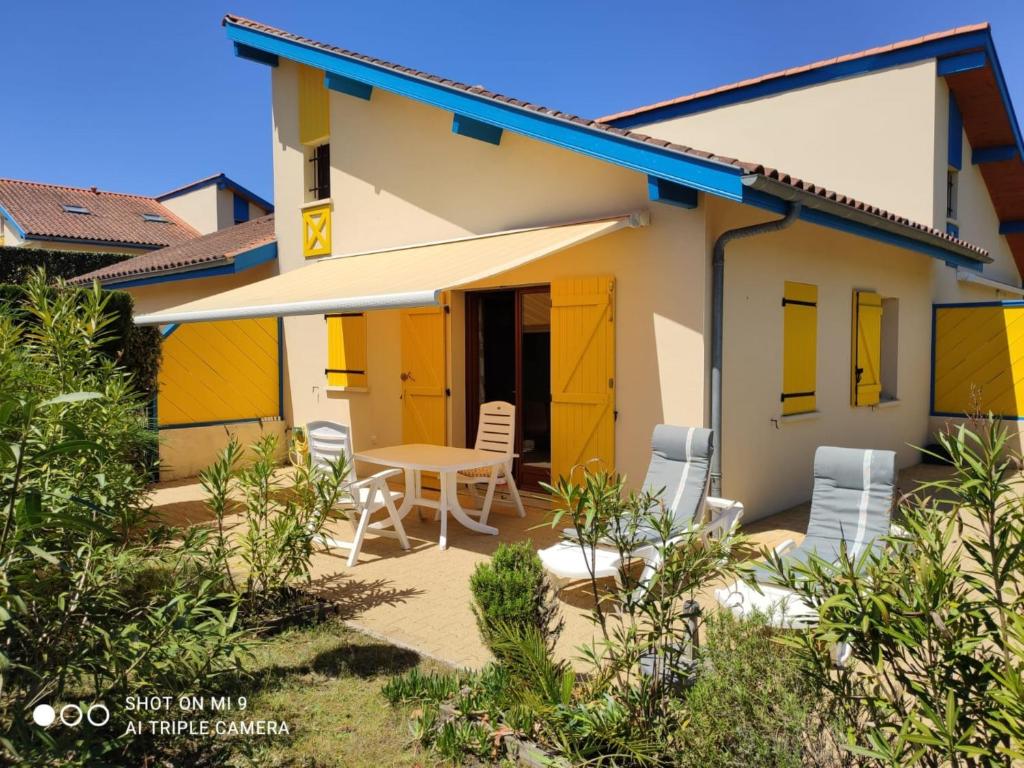 波讷地区圣朱利安Village Océlandes的一座带黄色门和桌椅的房子