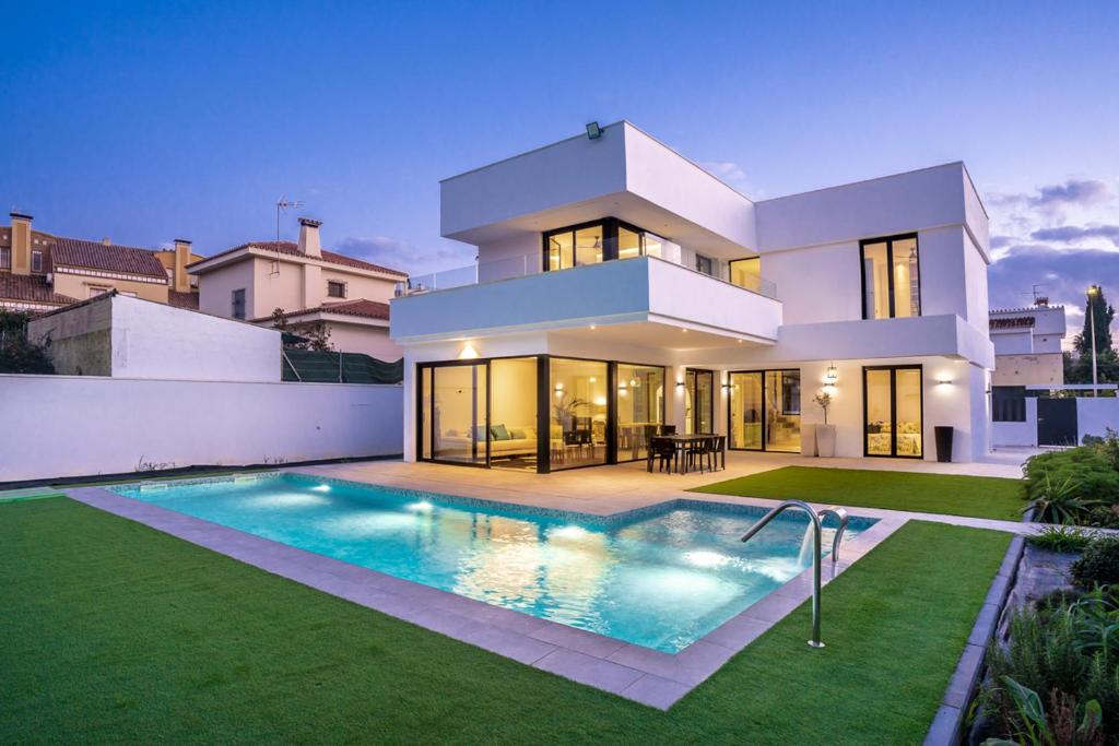 林孔-德拉维多利亚Villa swimming pool Malaga的一座大型白色房子,前面设有一个游泳池