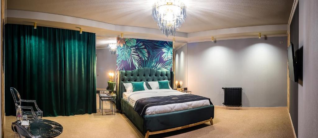 文尼察RICH Boutique-Hotel的一间卧室配有一张带绿色窗帘和吊灯的床。
