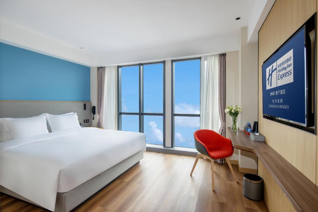 长沙长沙省府智选假日酒店的酒店客房带白色的床和红色椅子