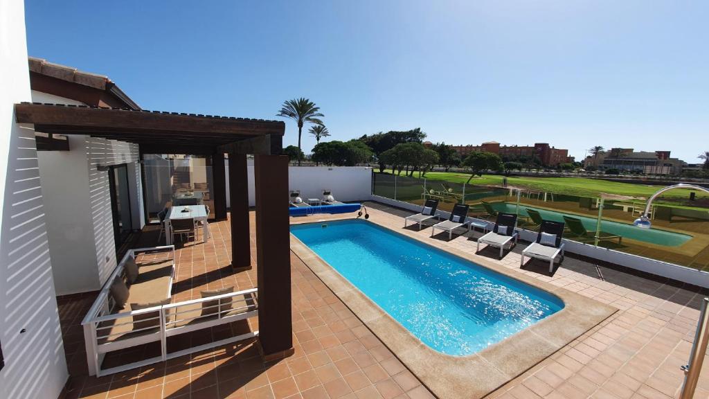 卡勒达德福斯特Villa BELLA on Golf in La Estancia, Caleta Fuste-Fuerteventura的一座带躺椅的游泳池位于大楼旁