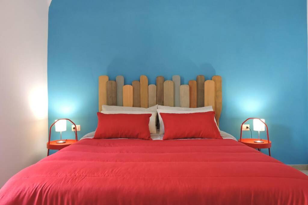 泰尔莫利Blue Sail Apartment的一张红色的床,配有两个红色枕头和蓝色的墙壁
