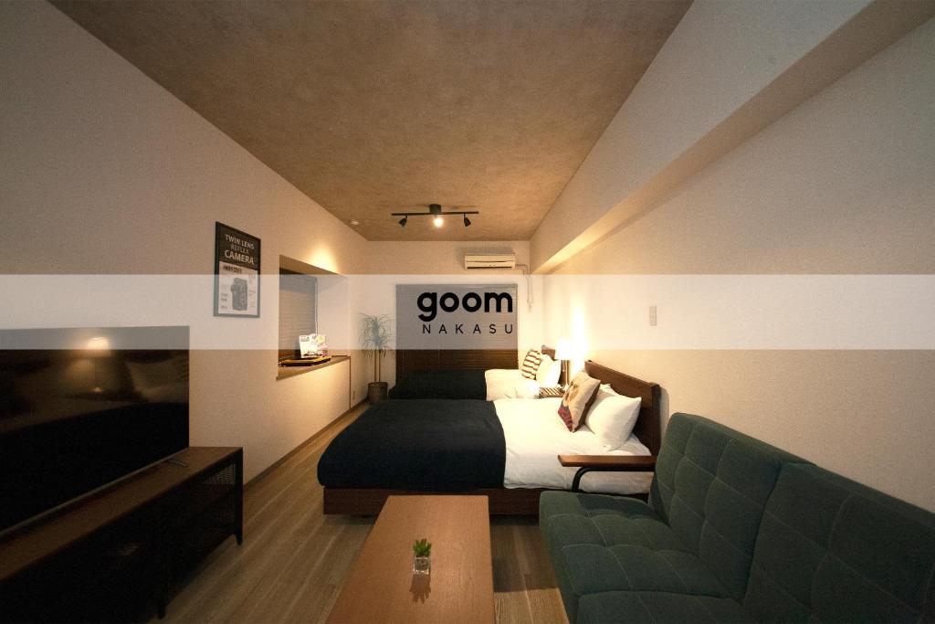 福冈goom Hotel Nakasu的一间卧室配有一张床、一张沙发和一台电视