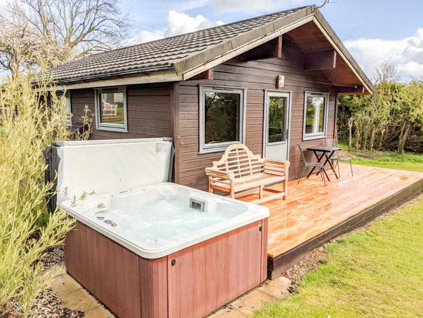 朗塞斯顿Avallon Lodges的木甲板上的热水浴池,带房子