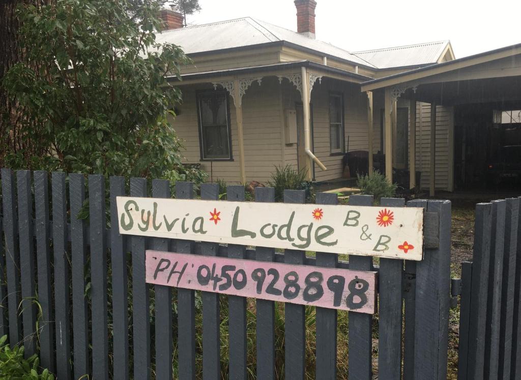 奥尔博斯特Sylvia Lodge A step back in time pet friendly Homestay的房屋前的栅栏上的一个标志