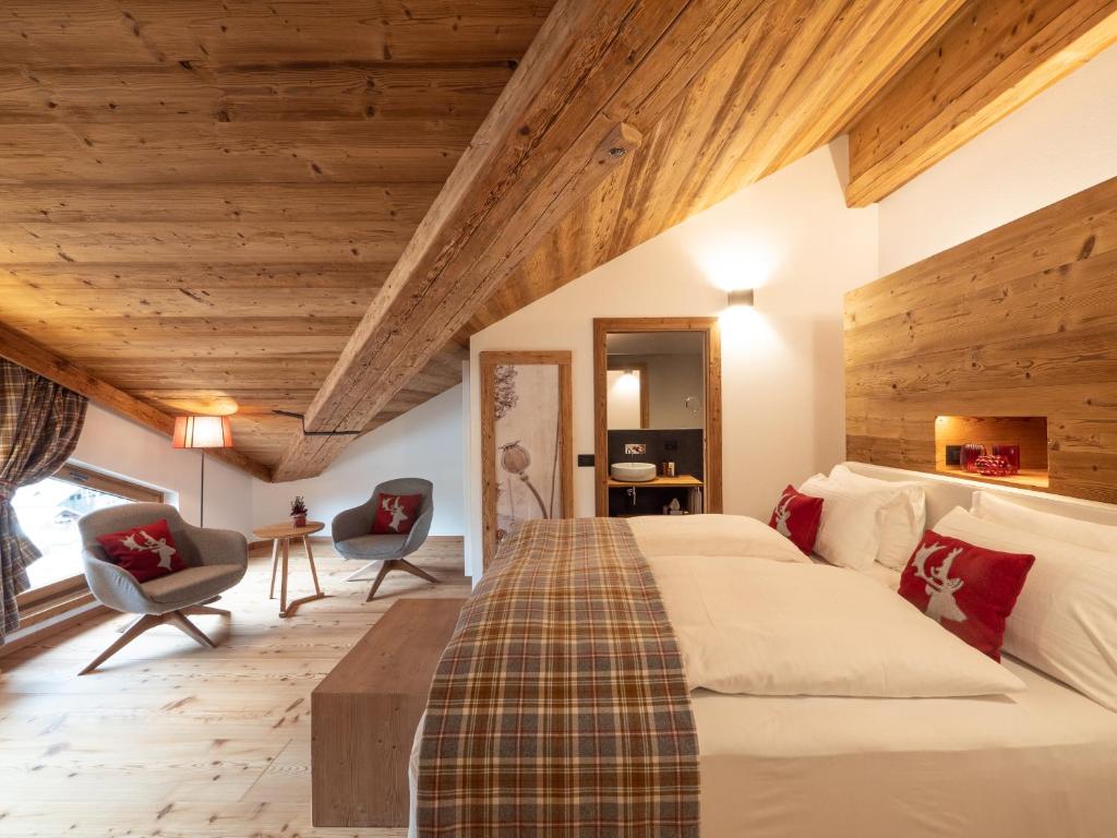 圣维托-迪卡多雷FIORI Dolomites Experience Hotel的一间卧室设有一张大床和木制天花板。