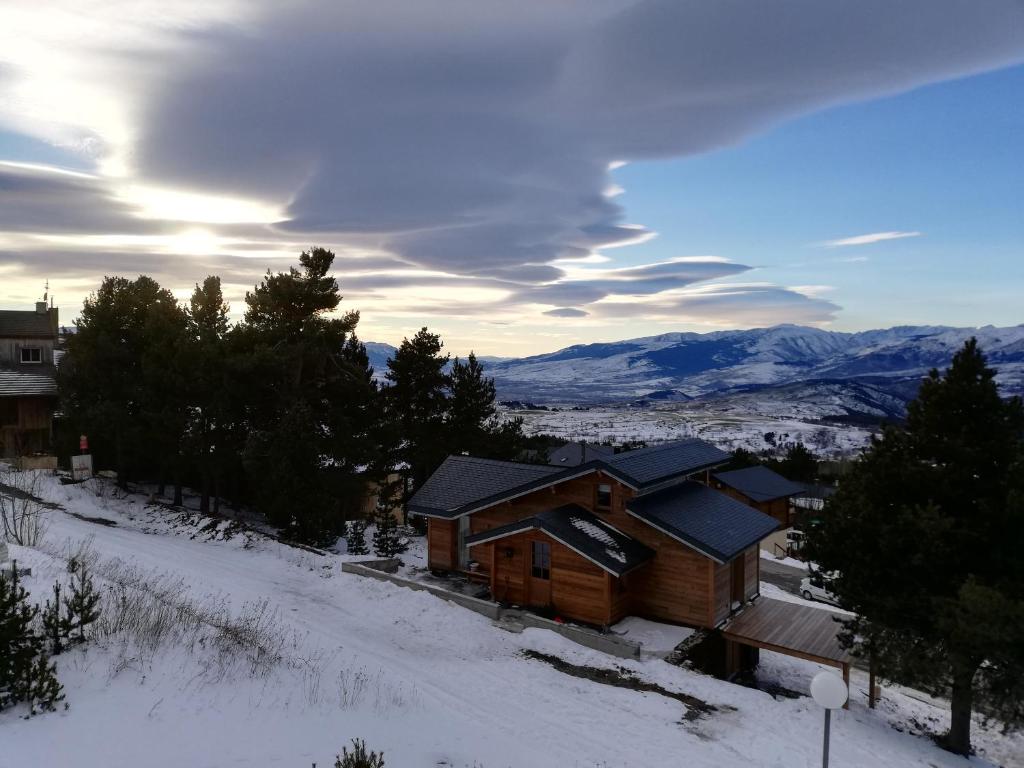 埃安Studio LUPIN Eyne pied de pistes的雪中小木屋,背景是群山