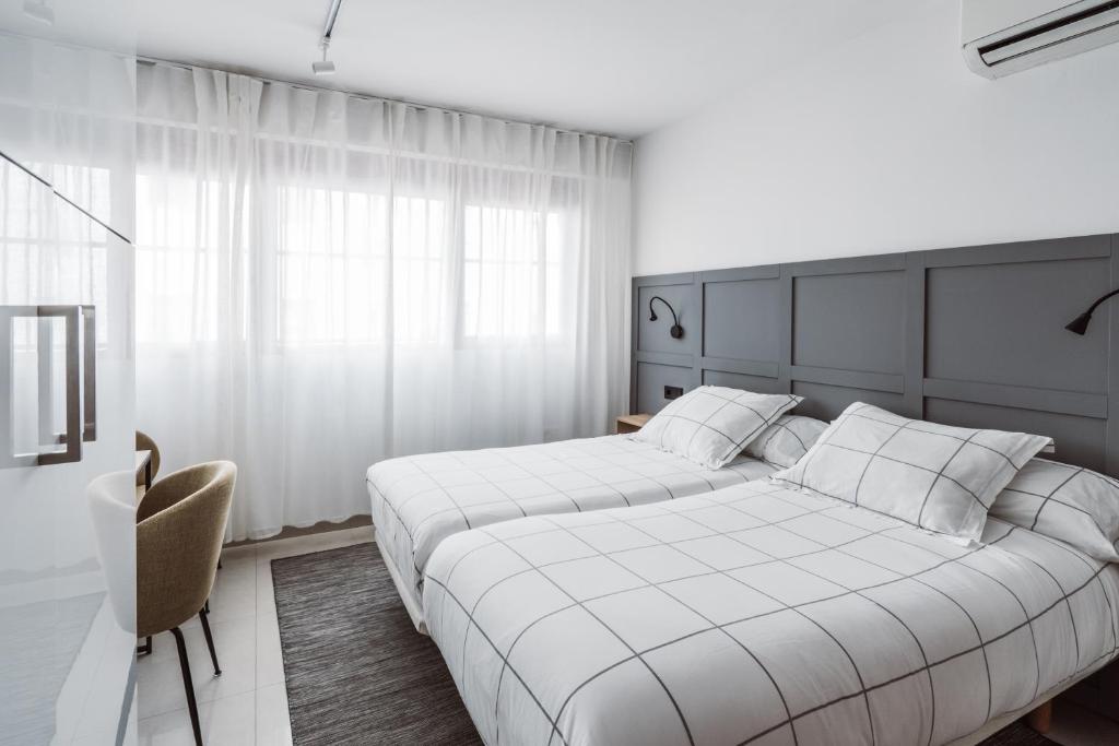 马德里Chamberí Suites的一间卧室配有两张床和椅子
