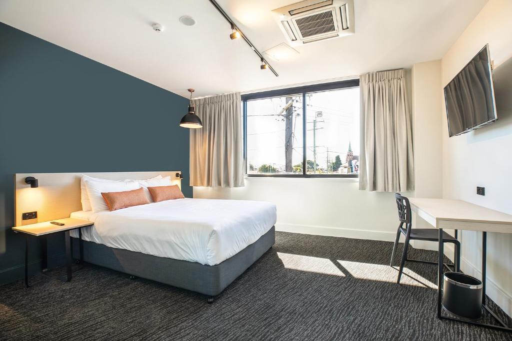 布里斯班查尔顿科纳奈特卡普酒店的配有一张床、一张书桌和一扇窗户的酒店客房