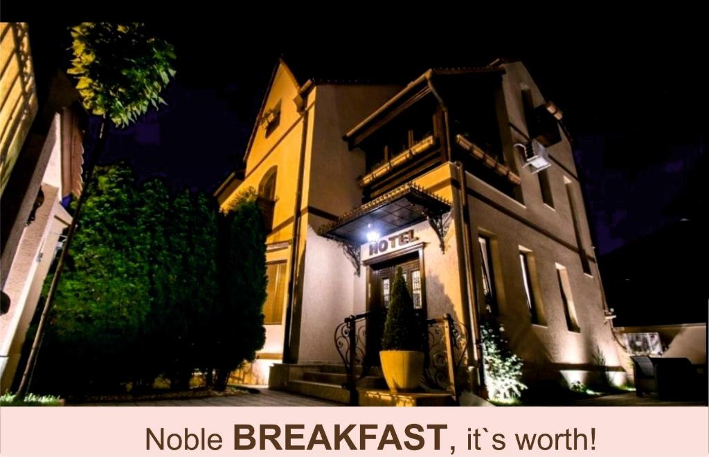 锡比乌Noblesse Boutique Resort的一座建筑,在晚上前方有标志