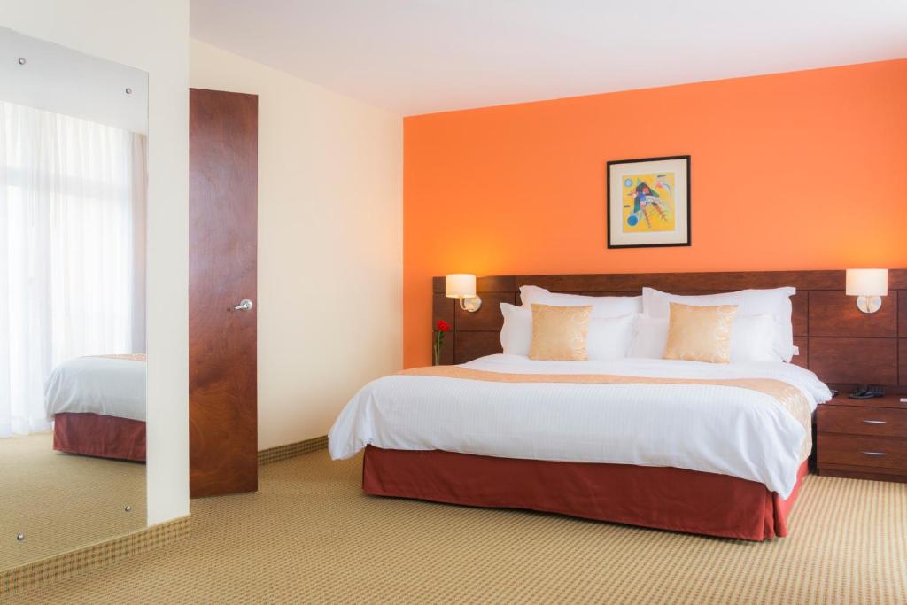 加拉加斯CONTINENTAL ALTAMIRA的酒店客房设有两张床和橙色的墙壁。