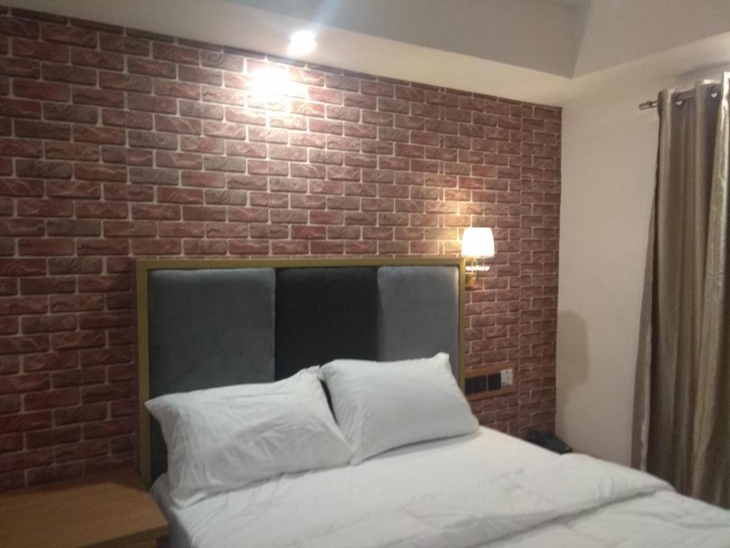 贝宁城Shamrockmanor(TheResidence)的一间有砖墙和一张床的卧室