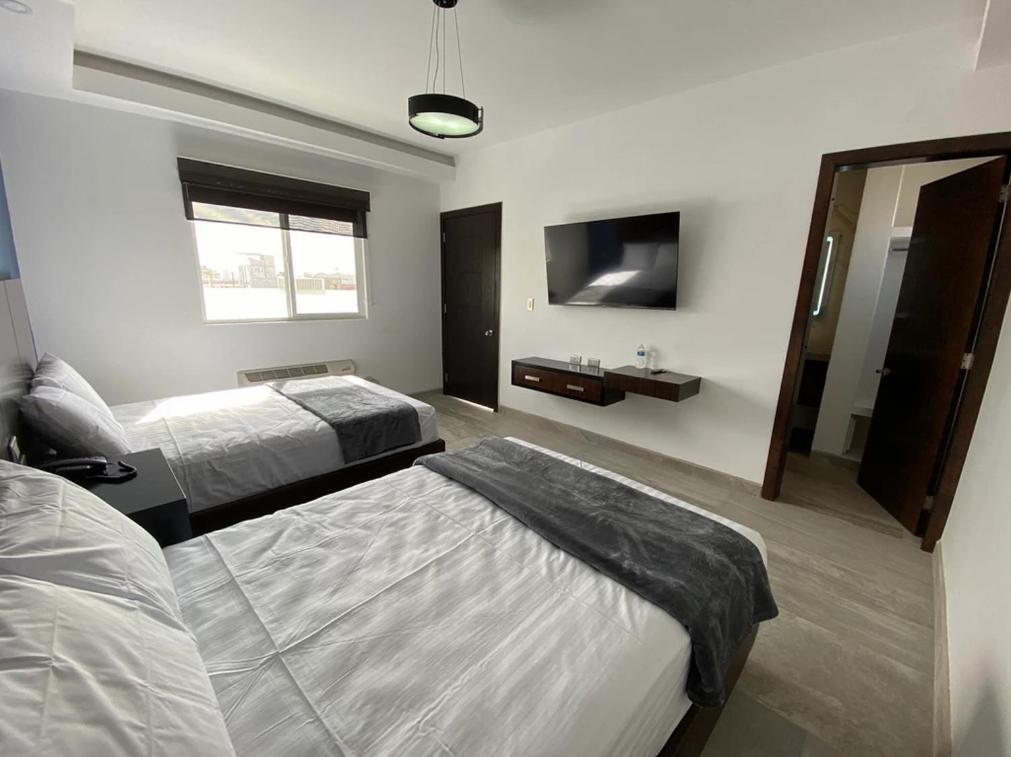 佩尼亚斯科港SAND MAR HOTEL的酒店客房设有两张床和电视。
