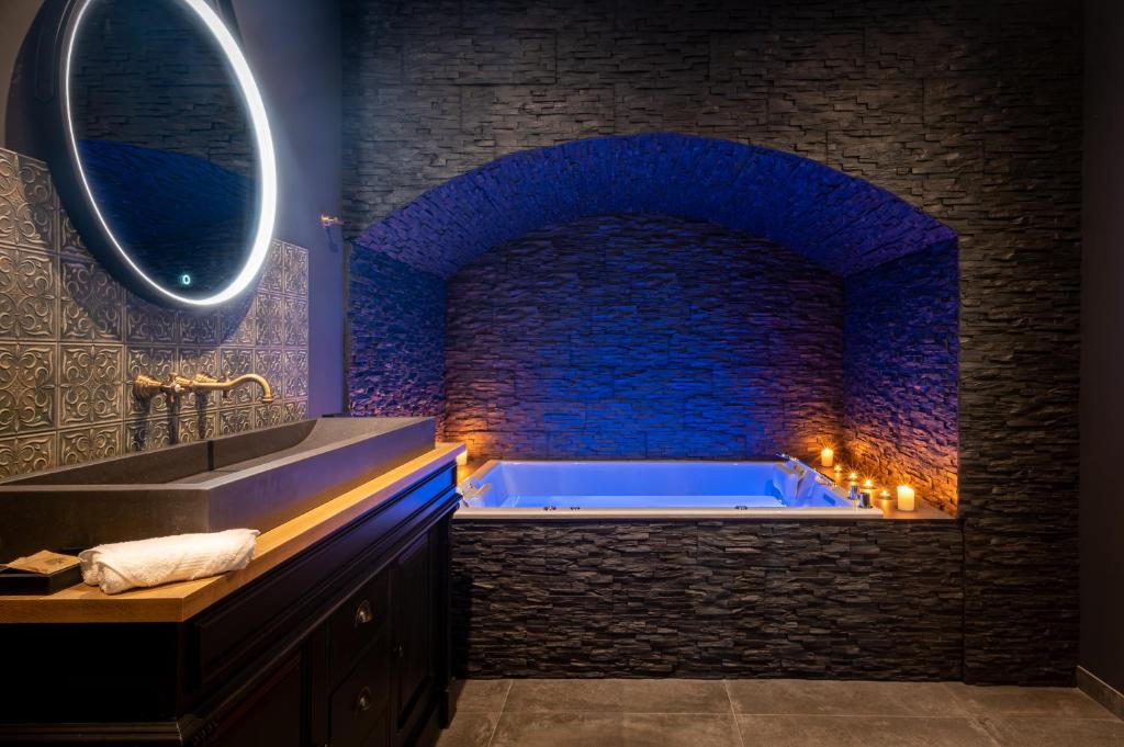 罗克布伦河畔阿尔让La Bastide du Rocher Boutique Hôtel & Spa的浴室配有带石墙的大浴缸