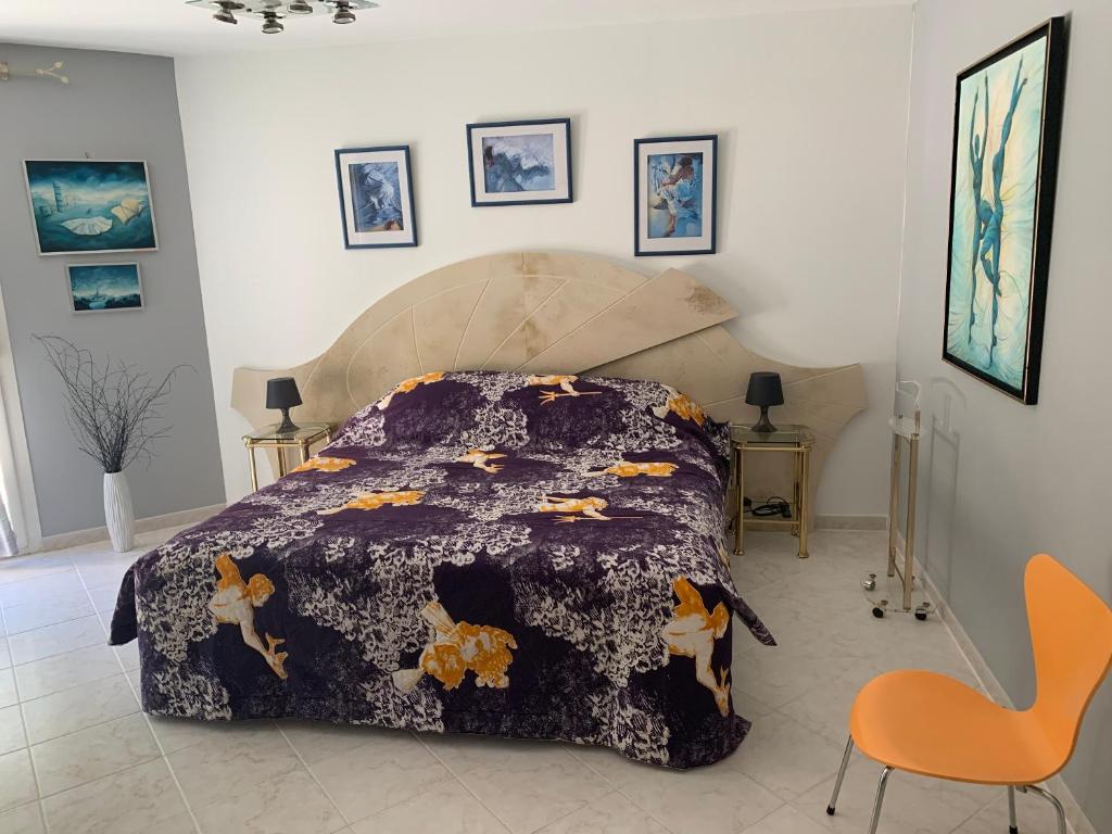 AnianeMAS FATINOU的一间卧室配有一张带紫色棉被的床