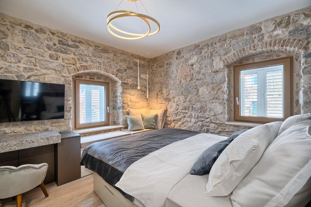 斯普利特Magnolia Luxury Rooms的一间卧室设有一张大床和石墙