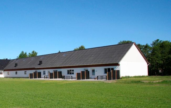 莱斯Gydensgaard ferielejligheder på Læsø的白色谷仓,有黑色的屋顶和绿色的场地