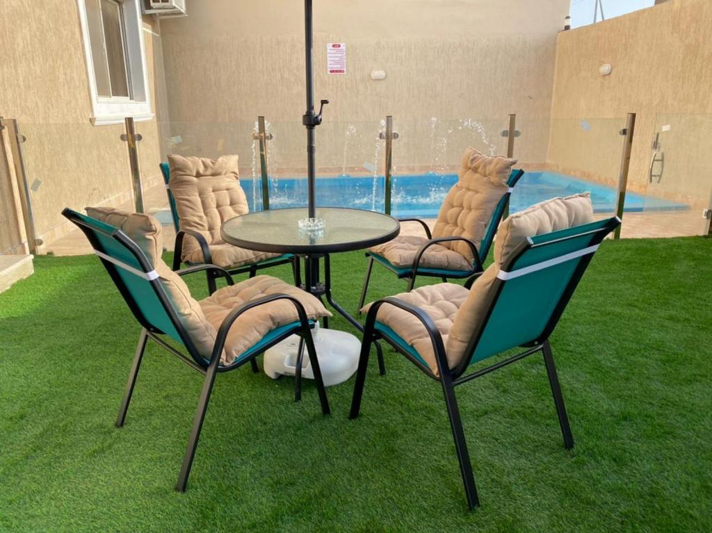 雷伊斯فيلا أمواج الشاطىء Amoaj beach的一组椅子、一张桌子和一个游泳池