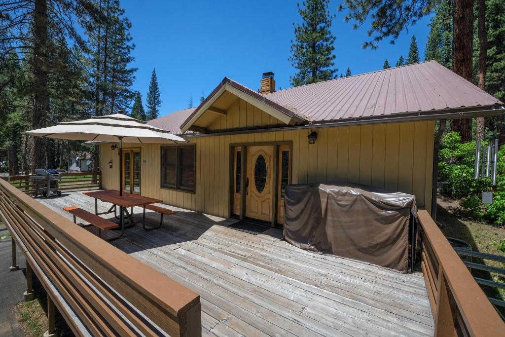西优胜美地Apple Tree Bear House的房屋设有1个带桌子和遮阳伞的甲板
