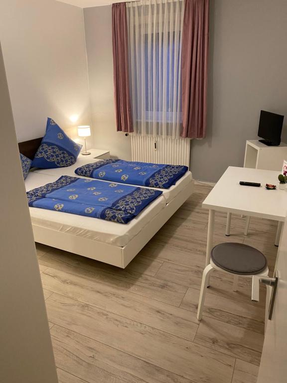 BetzdorfHotel Slavia的一间卧室配有一张带蓝色床单的床和一张书桌。