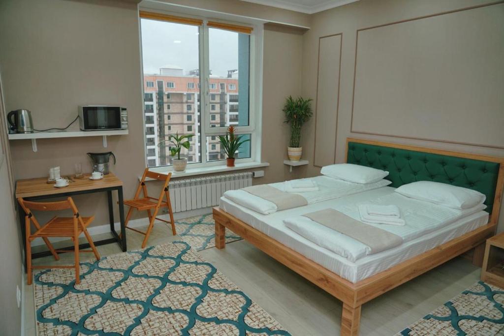 阿拉木图Halal Apart Hotel Almaty的一间卧室配有一张床、一张书桌和一个窗户。