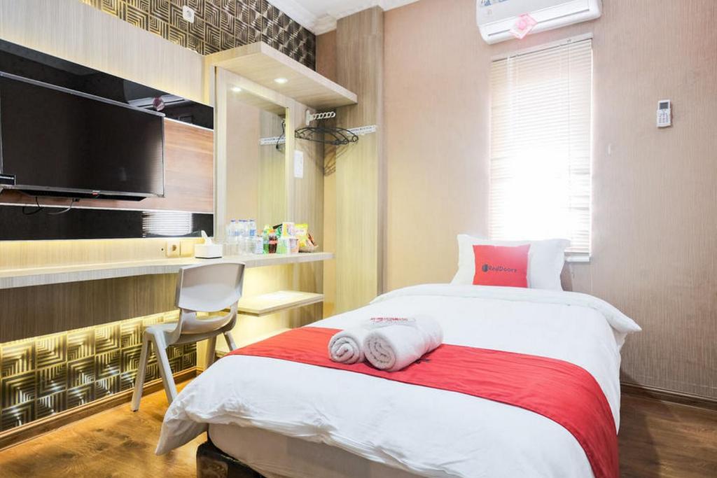 棉兰RedDoorz Plus @ Simpang USU Medan的一间卧室配有一张带椅子的床和一台电视