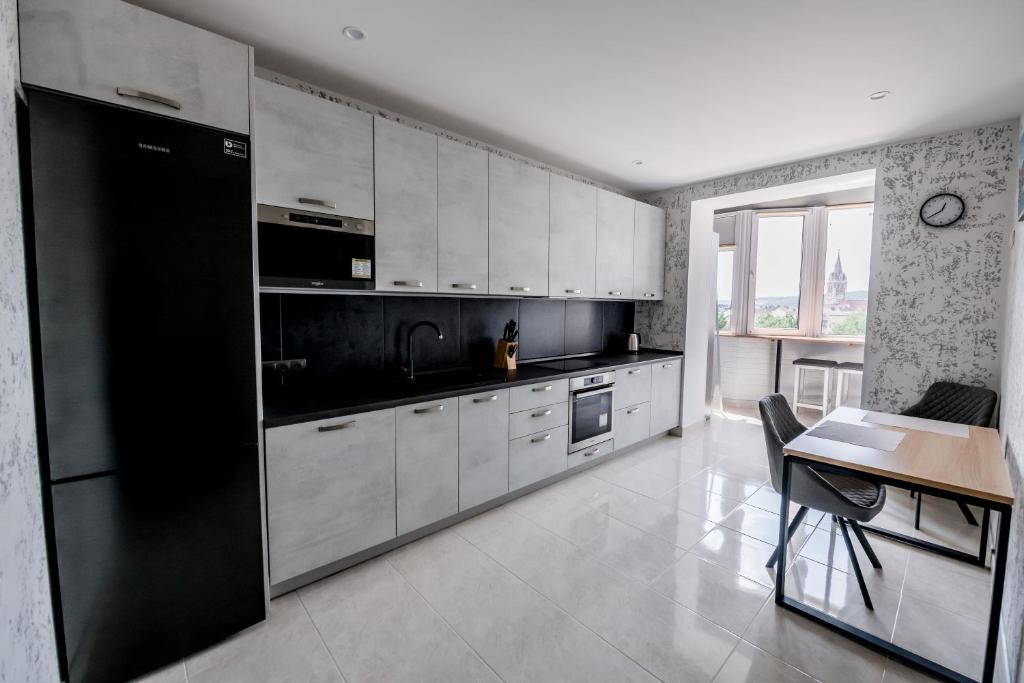 ChortkivАпартаменти OneDay в ценрі Чорткова的厨房配有白色橱柜和黑色冰箱。