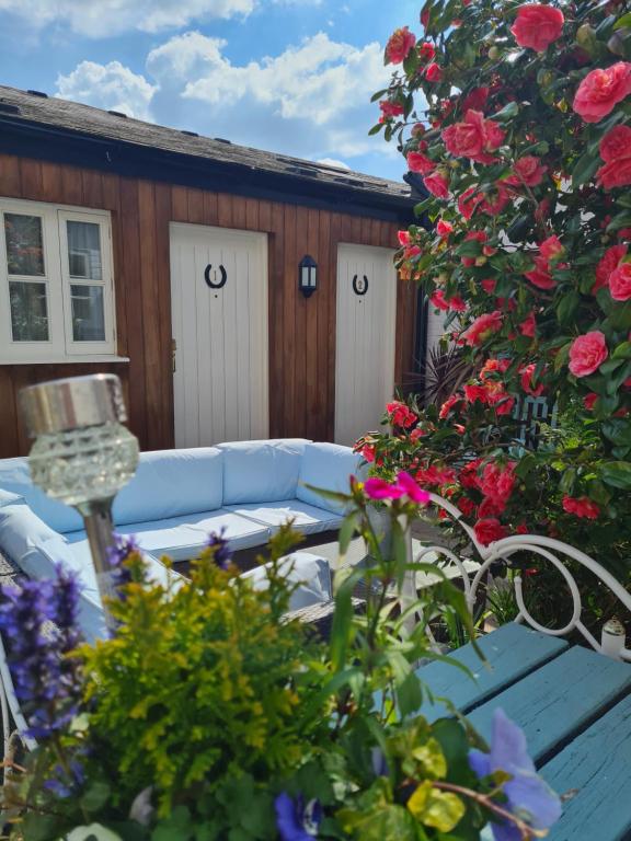 迪韦齐斯The Pelican Inn的一个带蓝色沙发的庭院,并种植了鲜花