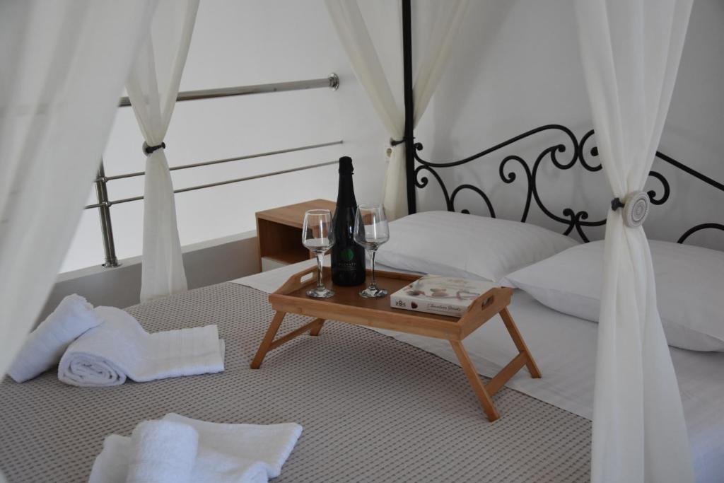 加拉塔斯Aphrodite's apartment的一间卧室配有一张带桌子、葡萄酒瓶和玻璃杯的床。