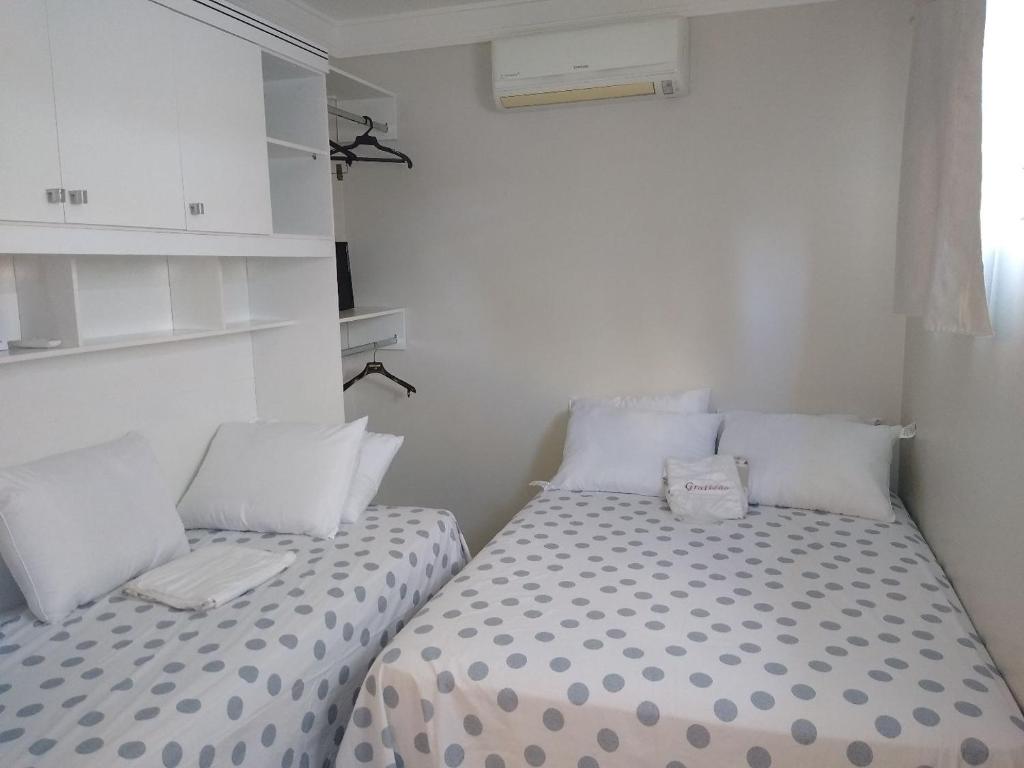 特雷西纳Apartamentos aconchegantes的配有白色墙壁的小客房内的两张床
