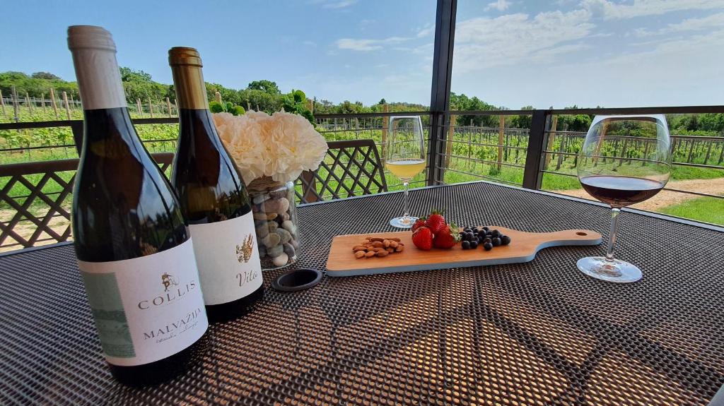 罗维尼Collis winery - Family & Friends - Mobilhome的2瓶葡萄酒和1盘水果放在桌子上