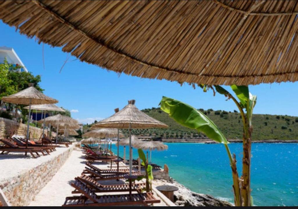 萨兰达Villa Xhefri的海滩上的一组椅子和遮阳伞