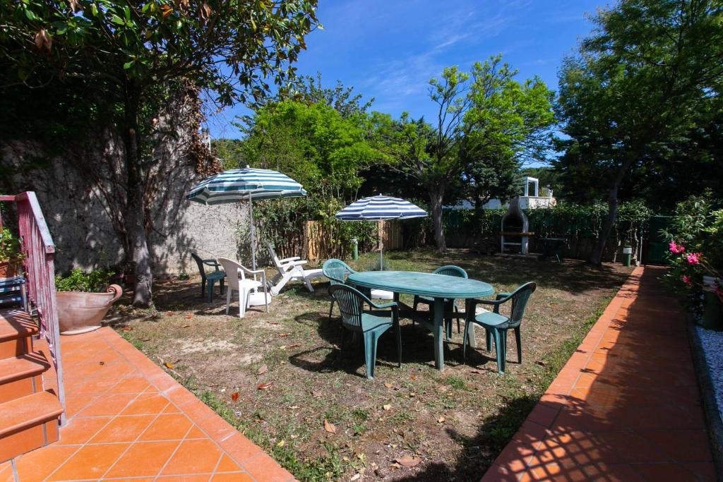 Casa PetromilliN232 - Numana, pentalocale con giardino in residence con piscina的一个带桌椅和遮阳伞的庭院