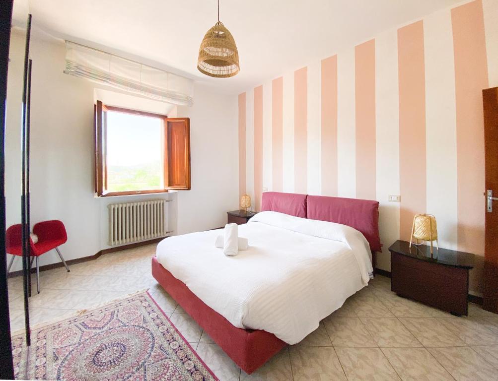 卢卡Cuore di Nozzano Castello的一间卧室配有一张大床和一张红色椅子