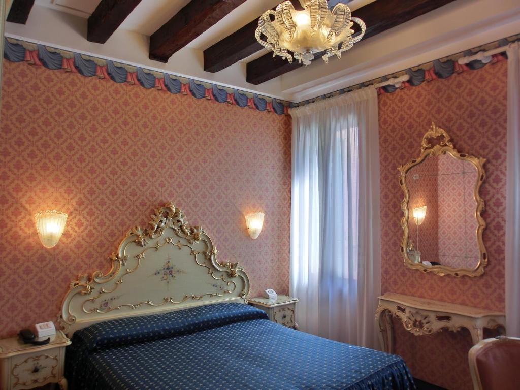 威尼斯戴安娜酒店的一间卧室配有蓝色的床和吊灯。