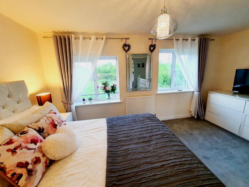 ShirebrookMeadow View, luxury home in heart of England的一间卧室设有一张大床和两个窗户。