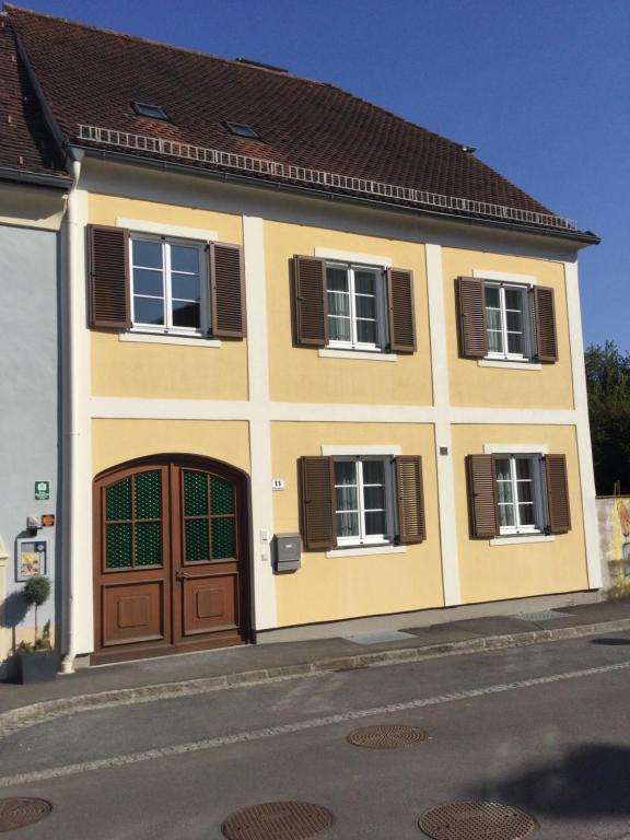 巴特拉德克斯堡ALTSTADT-APARTMENTS Bad Radkersburg - Ihr Zuhause auf Reisen的黄色的房子,设有棕色的门和窗户