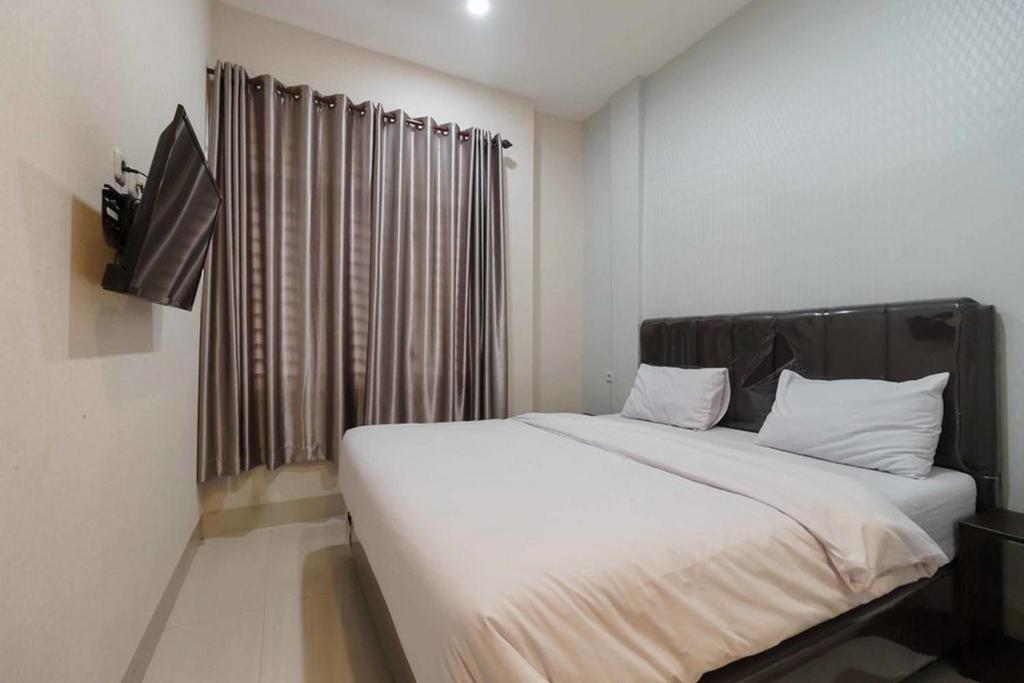 SunggalSeindo Hotel Mitra RedDoorz的卧室设有一张白色大床和一扇窗户。