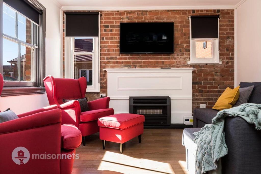 古尔本Elements Of Goulburn II的客厅配有红色家具和壁炉
