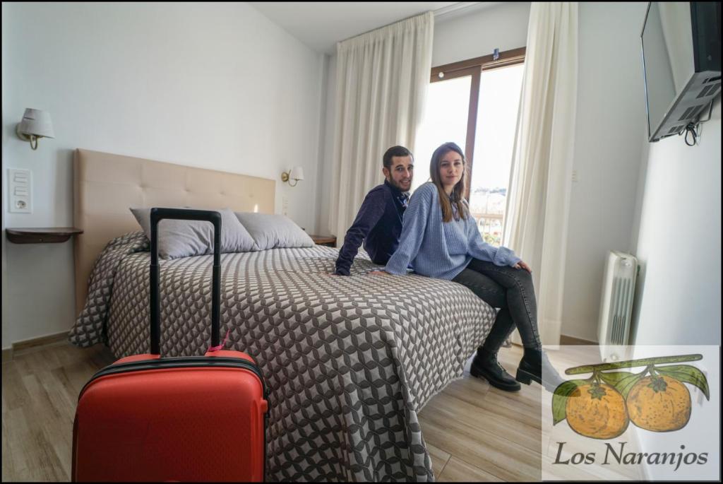 MelegisHostal y Apartamento Rural Los Naranjos的男人和女人带着行李坐在床上