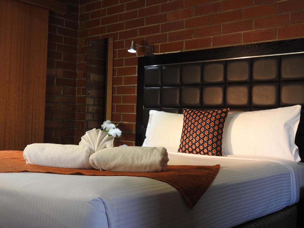Mawson Lakes普拉卡汽车旅馆的一间卧室配有一张床,上面有两条毛巾