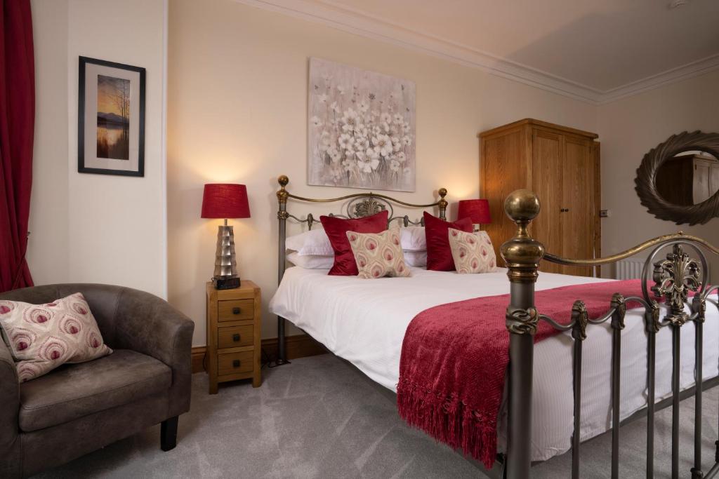 安布尔塞德梅尔罗斯宾馆的一间卧室配有一张带红色枕头的床和一把椅子