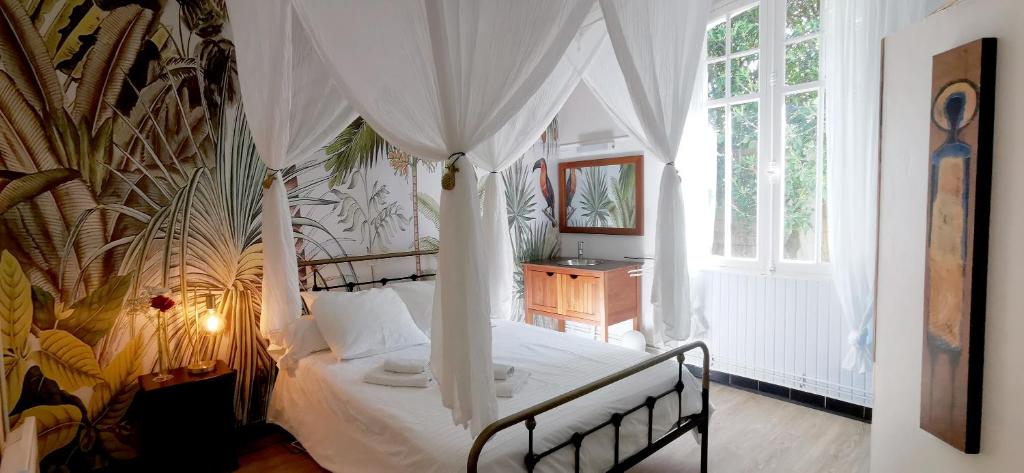 米尼赞海滩莱斯埃姆布伦斯酒店的一间卧室配有一张带天蓬的床和一张书桌