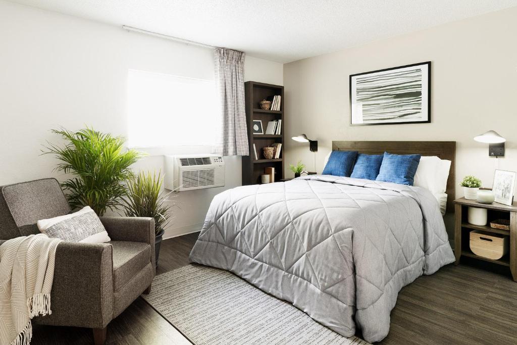 卡罗尔顿InTown Suites Extended Stay Carrollton TX - Westgrove Drive的卧室配有床、椅子和窗户。