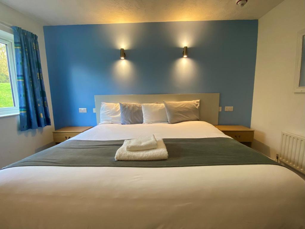 米尔顿凯恩斯National Badminton Centre Lodge & Health Club的一间卧室设有一张蓝色墙壁的大床