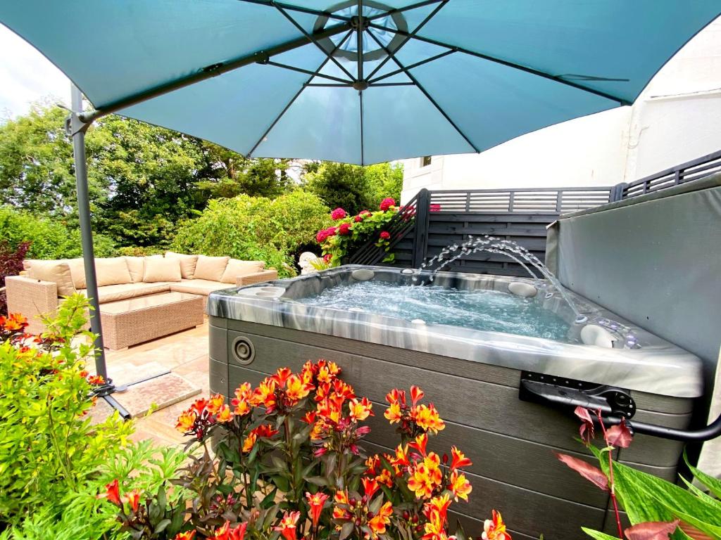 托基The Town House at Muntham- Luxury Holiday Home with Hot Tub的花园内的热水浴池,配有遮阳伞