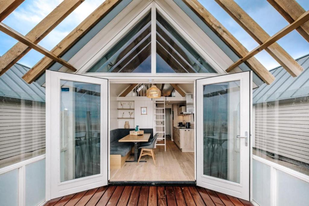 赞德沃特Thalassa Beach Houses的玻璃延伸到一个小房子,里面配有餐桌