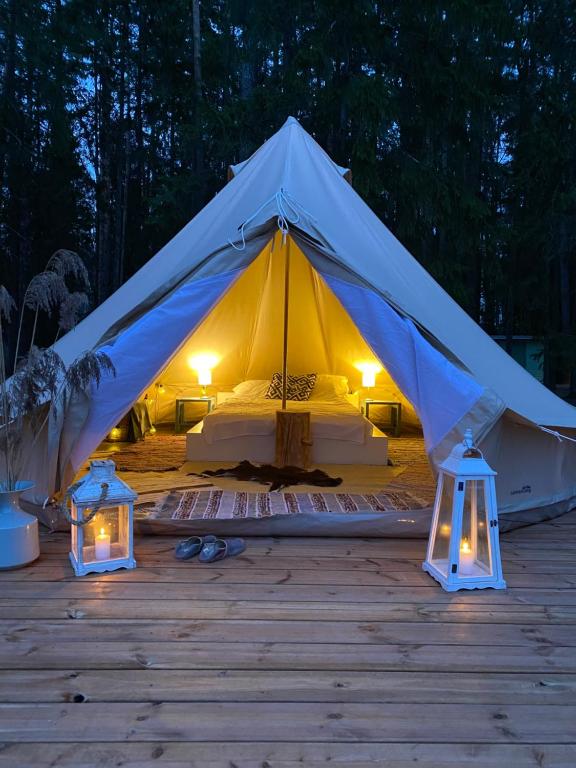 TromsiSaarjärve Puhkemaja Glämping的木制甲板上配有床和灯的帐篷